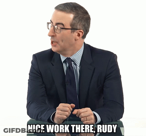A Man In A Suit And Tie Is Sitting At A Desk And Says Nice Work There Rudy GIF