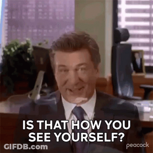 A Man In A Suit And Tie Is Sitting At A Desk And Smiling . GIF