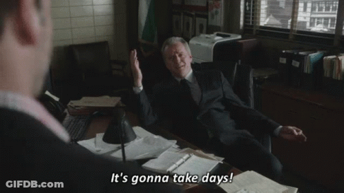 A Man In A Suit And Tie Is Sitting At A Desk And Talking To Another Man In A Suit And Tie . GIF