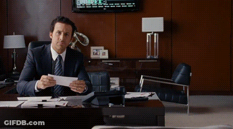 A Man In A Suit And Tie Is Sitting At A Desk Holding A Piece Of Paper With The Words So I Was Right Behind Him GIF