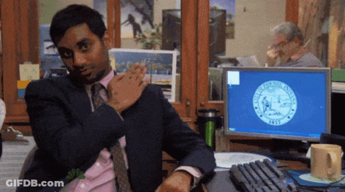 A Man In A Suit And Tie Is Sitting At A Desk In Front Of A Computer Screen That Says New York State Seal On It GIF