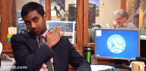 A Man In A Suit And Tie Is Sitting At A Desk In Front Of A Computer With A Seal On It GIF