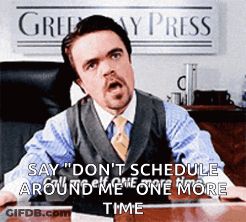 A Man In A Suit And Tie Is Sitting At A Desk In Front Of A Sign That Says " Greenway Press " GIF