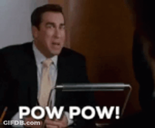 A Man In A Suit And Tie Is Sitting At A Desk With A Laptop And The Words Pow Pow . GIF