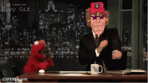 A Man In A Suit And Tie Is Sitting At A Desk With A Mug That Says Let 'S Get This Talk On It GIF