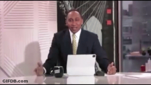 A Man In A Suit And Tie Is Sitting At A Desk With A Tablet And A Cup That Says Trust On It GIF