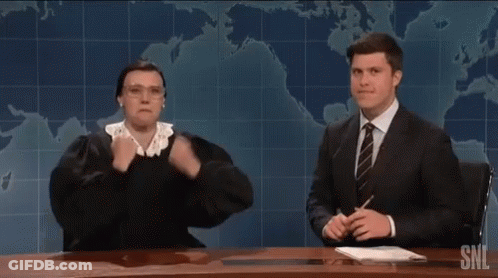 A Man In A Suit And Tie Is Sitting At A Desk With A Woman In A Judge 'S Outfit . GIF