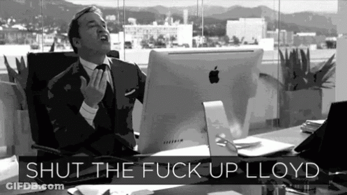A Man In A Suit And Tie Is Sitting At A Desk With An Apple Computer And The Words Shut The Fuck Up Lloyd Above Him GIF