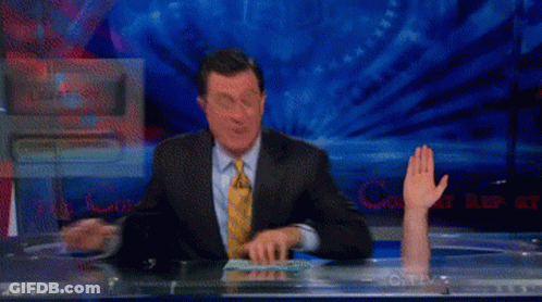 A Man In A Suit And Tie Is Sitting At A Desk With His Hand Up In Front Of A Screen That Says Cnn GIF
