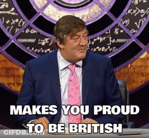 A Man In A Suit And Tie Is Sitting At A Desk With The Words Makes You Proud To Be British Below Him GIF
