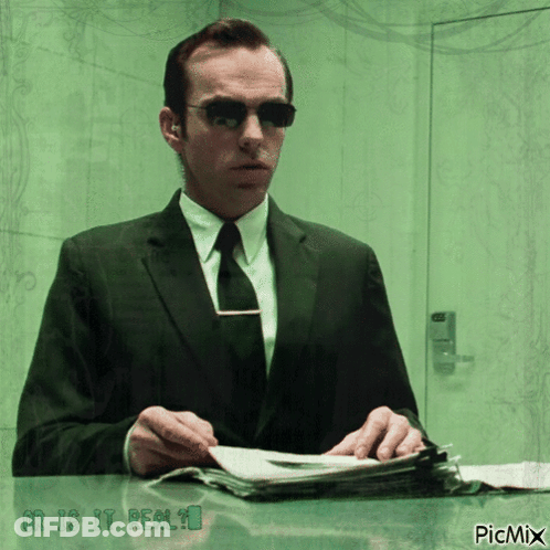 A Man In A Suit And Tie Is Sitting At A Desk With The Words " Or Is It Real " On The Bottom GIF