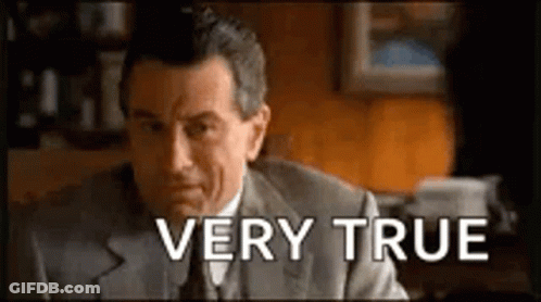 A Man In A Suit And Tie Is Sitting At A Desk With The Words `` Very True '' Written Above Him . GIF
