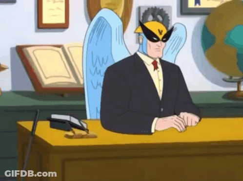 A Man In A Suit And Tie Is Sitting At A Desk GIF