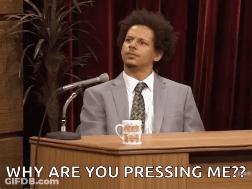 A Man In A Suit And Tie Is Sitting At A Podium Asking Why Are You Pressing Me .. GIF