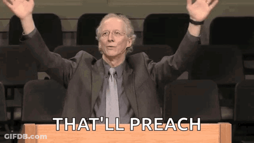A Man In A Suit And Tie Is Sitting At A Podium With His Arms In The Air And Says That 'Ll Preach GIF