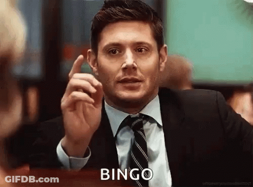 A Man In A Suit And Tie Is Sitting At A Table And Pointing Up With His Finger . GIF