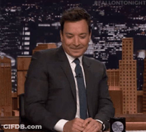 A Man In A Suit And Tie Is Sitting At A Table And Says Maaaa Maybe GIF