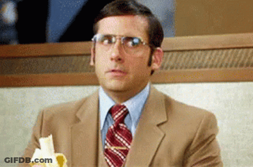 A Man In A Suit And Tie Is Sitting At A Table Eating A Banana GIF
