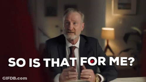 A Man In A Suit And Tie Is Sitting At A Table Holding A Cup Of Coffee And Talking . GIF
