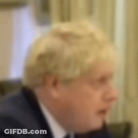 A Man In A Suit And Tie Is Sitting At A Table . GIF