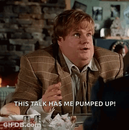 A Man In A Suit And Tie Is Sitting At A Table In A Restaurant And Talking To Someone . GIF