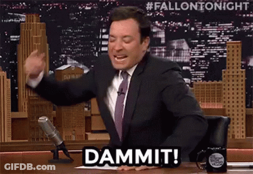 A Man In A Suit And Tie Is Sitting At A Table In Front Of A Microphone And Says Dammit . GIF