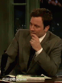 A Man In A Suit And Tie Is Sitting At A Table With A Book On It That Says Al Robert GIF