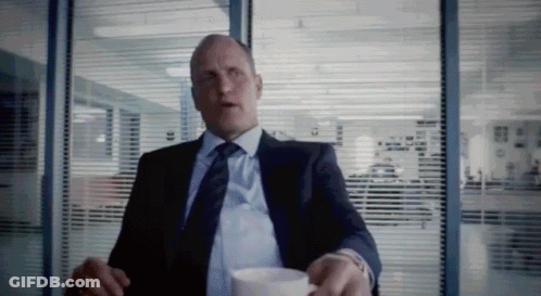 A Man In A Suit And Tie Is Sitting At A Table With A Cup Of Coffee . GIF