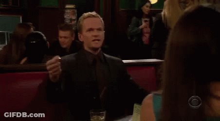 A Man In A Suit And Tie Is Sitting At A Table With A Glass Of Wine . GIF