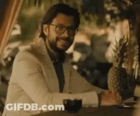 A Man In A Suit And Tie Is Sitting At A Table With A Glass Of Wine . GIF