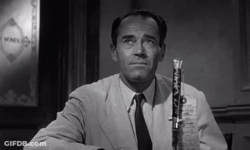 A Man In A Suit And Tie Is Sitting At A Table With A Microphone In Front Of Him GIF