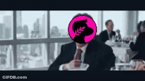 A Man In A Suit And Tie Is Sitting At A Table With A Pink Circle In Front Of His Head . GIF