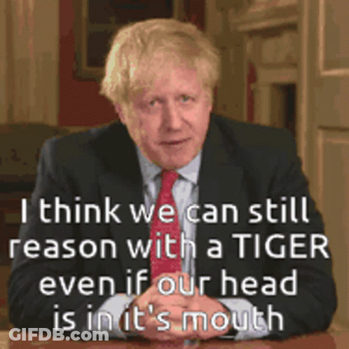A Man In A Suit And Tie Is Sitting At A Table With A Quote Behind Him GIF