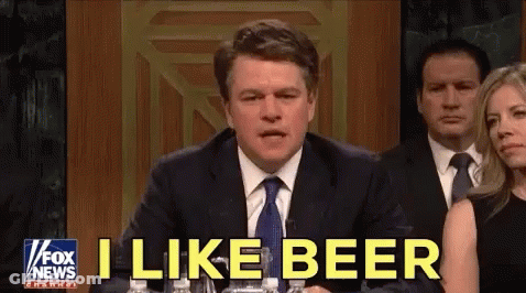 A Man In A Suit And Tie Is Sitting At A Table With Bottles Of Water And Says I Like Beer . GIF