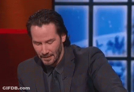 A Man In A Suit And Tie Is Sitting At A Table With His Eyes Closed . GIF