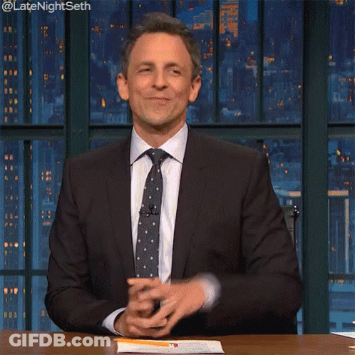 A Man In A Suit And Tie Is Sitting At A Table With His Eyes Closed GIF