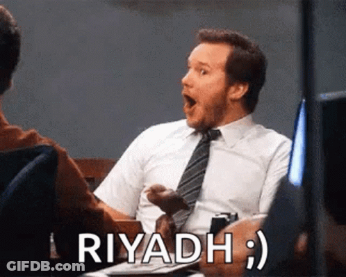 A Man In A Suit And Tie Is Sitting At A Table With His Mouth Open And The Word Riyadh Written Next To Him . GIF