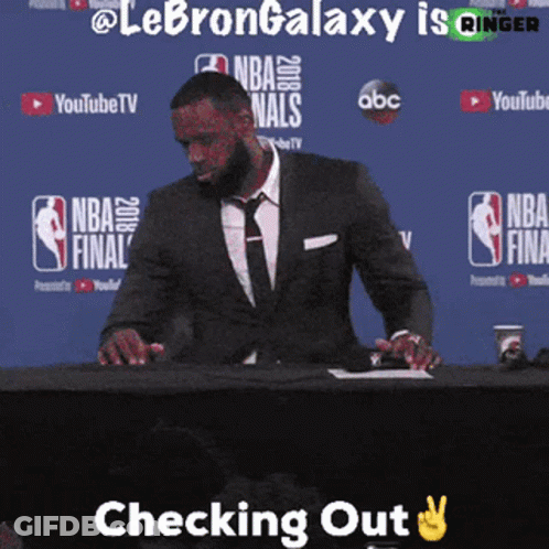 A Man In A Suit And Tie Is Sitting At A Table With The Words Checking Out Above Him GIF