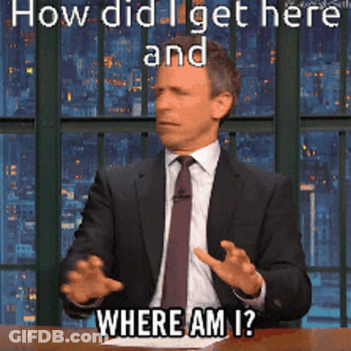 A Man In A Suit And Tie Is Sitting At A Table With The Words How Did I Get Here And Where Am I GIF