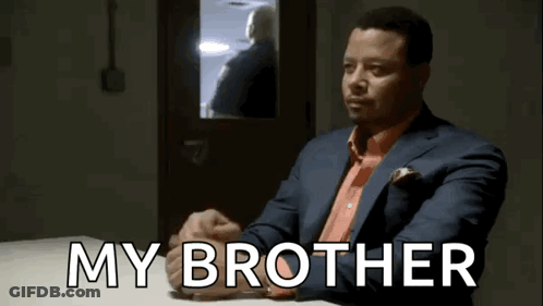 A Man In A Suit And Tie Is Sitting At A Table With The Words My Brother Written On It . GIF