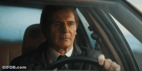 A Man In A Suit And Tie Is Sitting In A Car GIF