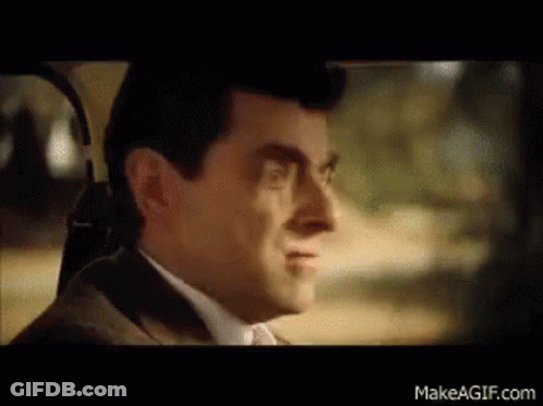 A Man In A Suit And Tie Is Sitting In A Car And Smiling . GIF