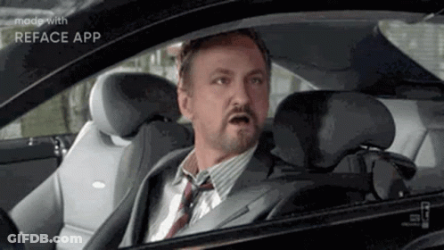 A Man In A Suit And Tie Is Sitting In A Car . GIF
