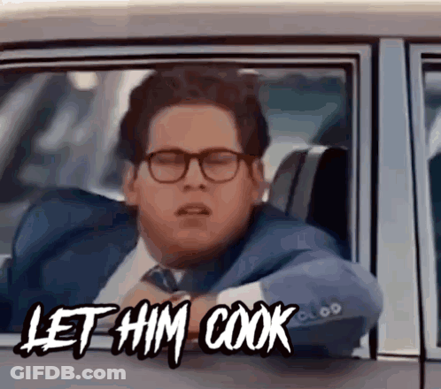 A Man In A Suit And Tie Is Sitting In A Car With The Words Let Him Cook Above Him GIF