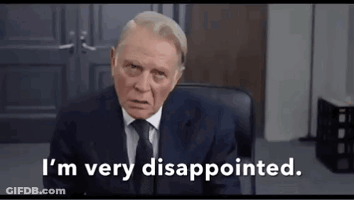 A Man In A Suit And Tie Is Sitting In A Chair . GIF