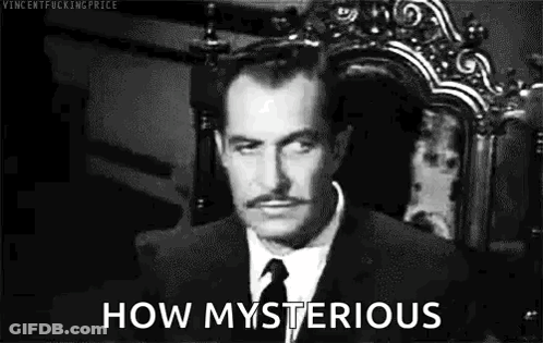 A Man In A Suit And Tie Is Sitting In A Chair And Looking At The Camera . GIF