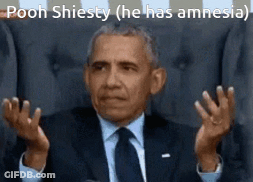 A Man In A Suit And Tie Is Sitting In A Chair And Making A Funny Face With His Hands Outstretched . GIF