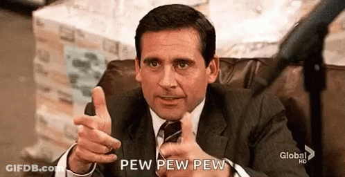 A Man In A Suit And Tie Is Sitting In A Chair Giving A Thumbs Up . GIF