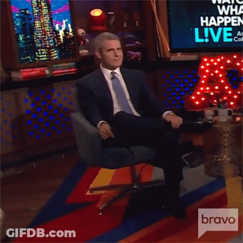 Man In Suit Sitting In Front Of Bravo Sign GIF