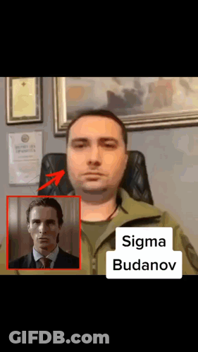 A Man In A Suit And Tie Is Sitting In A Chair Next To A Picture Of A Man Named Sigma Budenov GIF